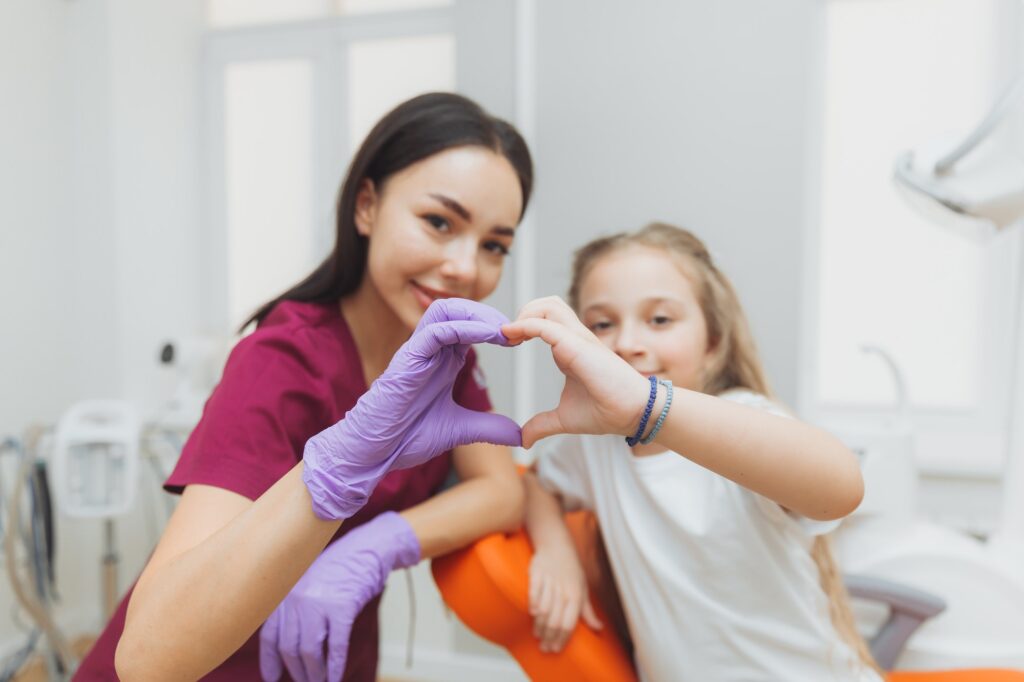 Selective focus of hands of dentist and little girl patient in heart shape